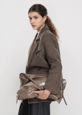 Woman holding a brown leather handbag against a white background